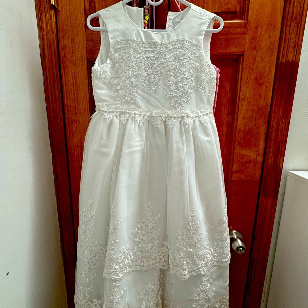 A sleeveless white dress with floral lace on the bodice and a tiered skirt.